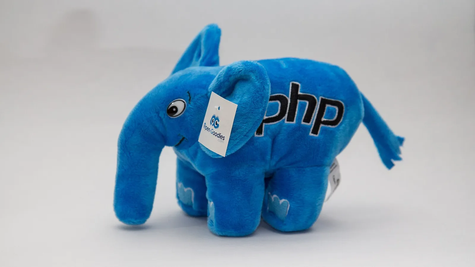 Синий плюшевый слонёнок с вышитым логотипом php на светлом фоне