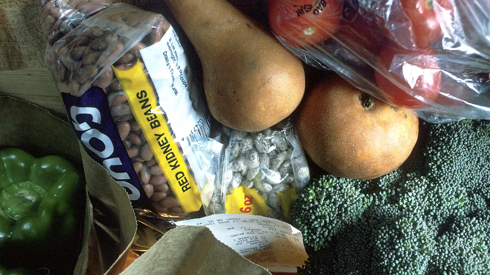 Бумажный пакет с продуктами: брокколи, груши, помидоры, сладкий перец и фасоль в упаковке