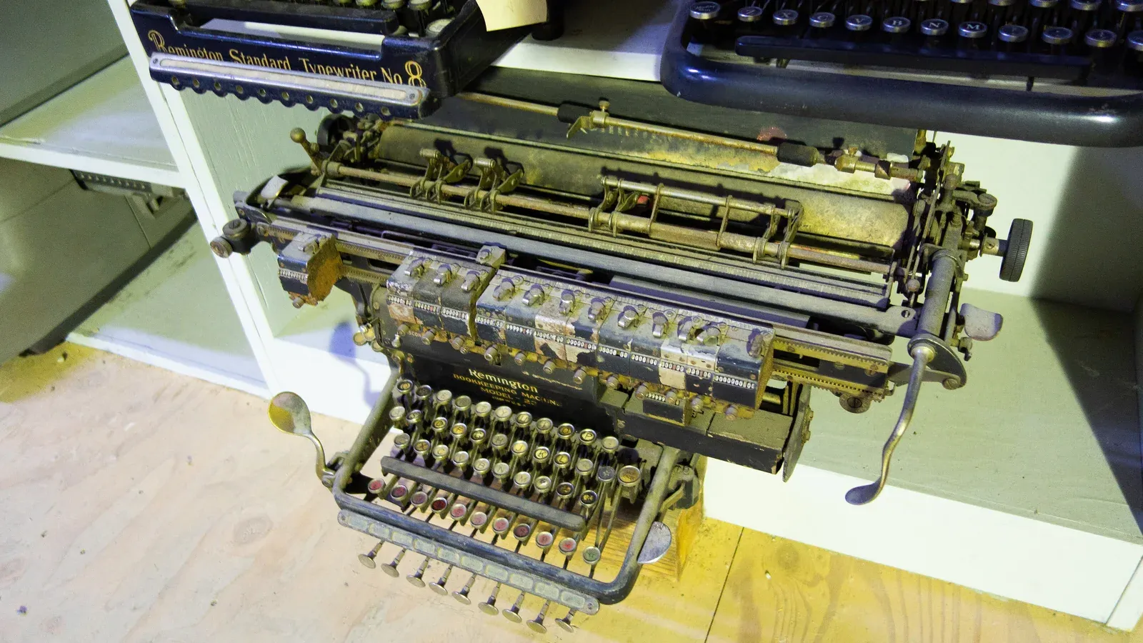 Старинная бухгалтерская машина Remington с двумя клавиатурами и кареткой на деревянной полке