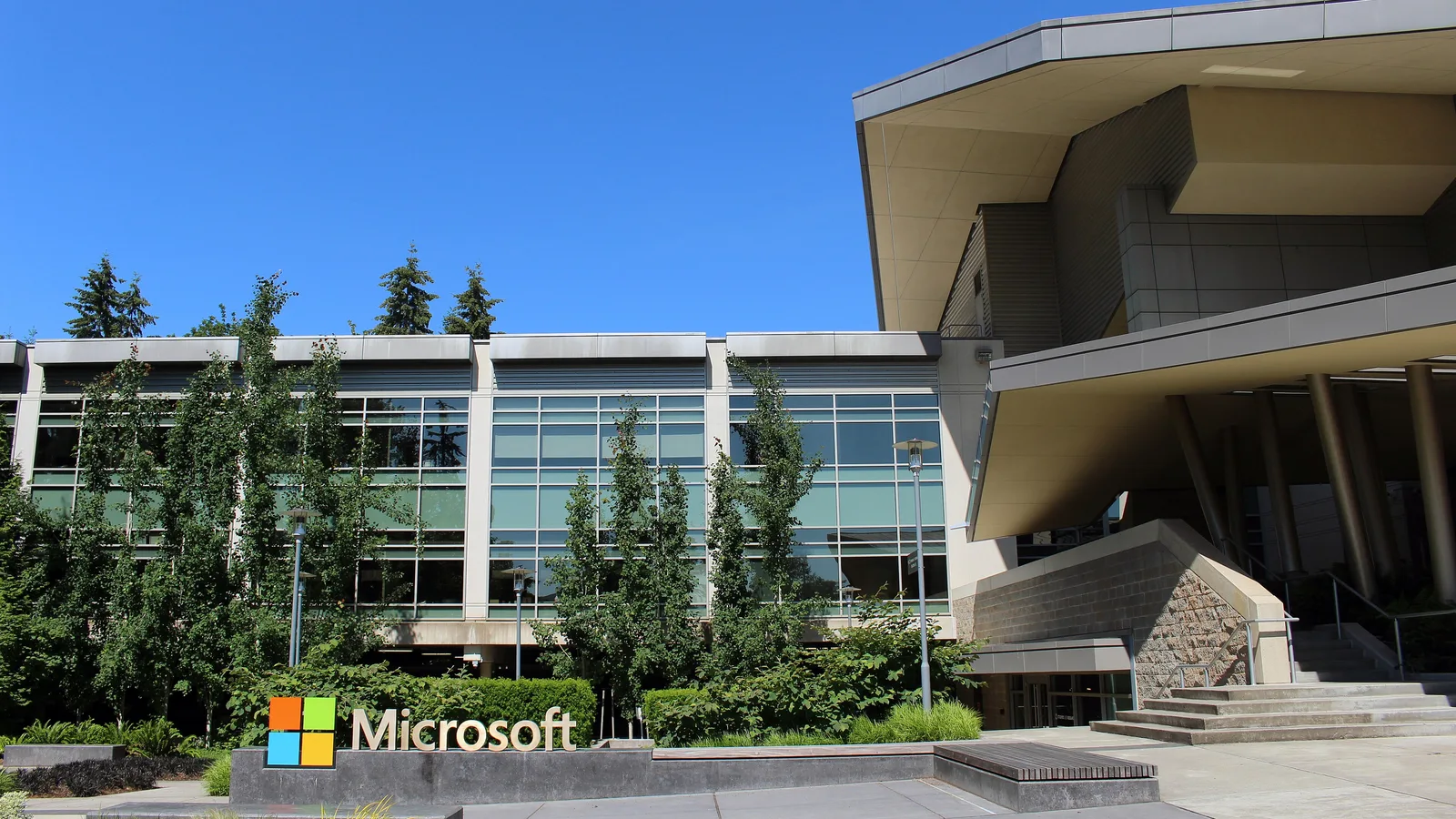 Стеклянное здание Microsoft в Редмонде и вывеска компании на газоне перед входом